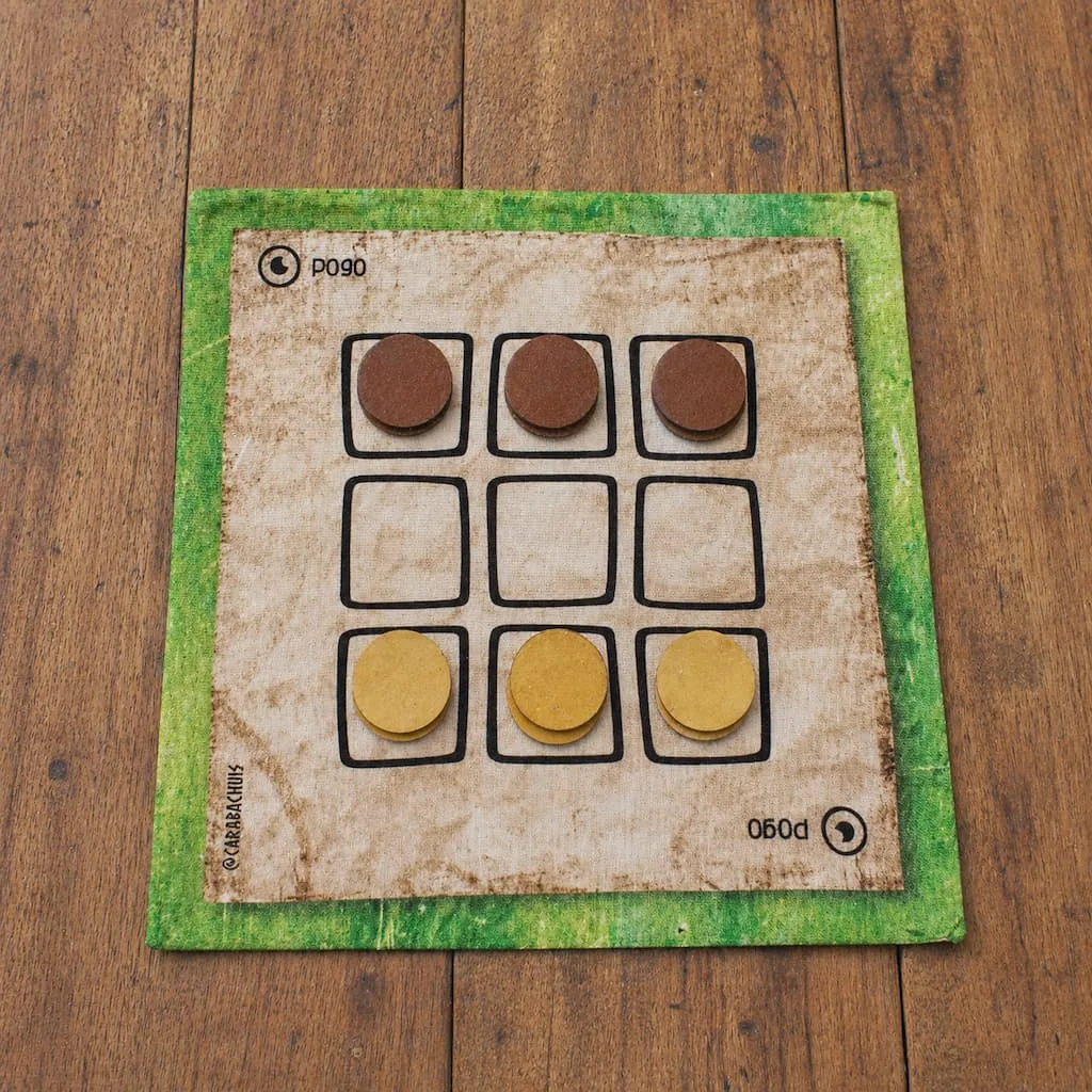 Tablero de Pogo extendido sobre una mesa de madera, las piezas están dispuestas en la posición inicial.