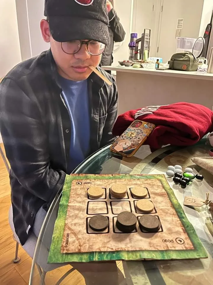 Jugador concentrado frente al tablero del Pogo de Carabachuis, juego abstracto portátil con fichas apiladas