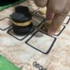 Detalle de jugada en el Pogo, piezas de madera apiladas en tablero 3x3 de Carabachuis