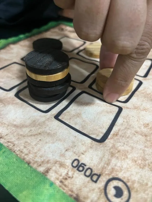 Detalle de jugada en el Pogo, piezas de madera apiladas en tablero 3x3 de Carabachuis