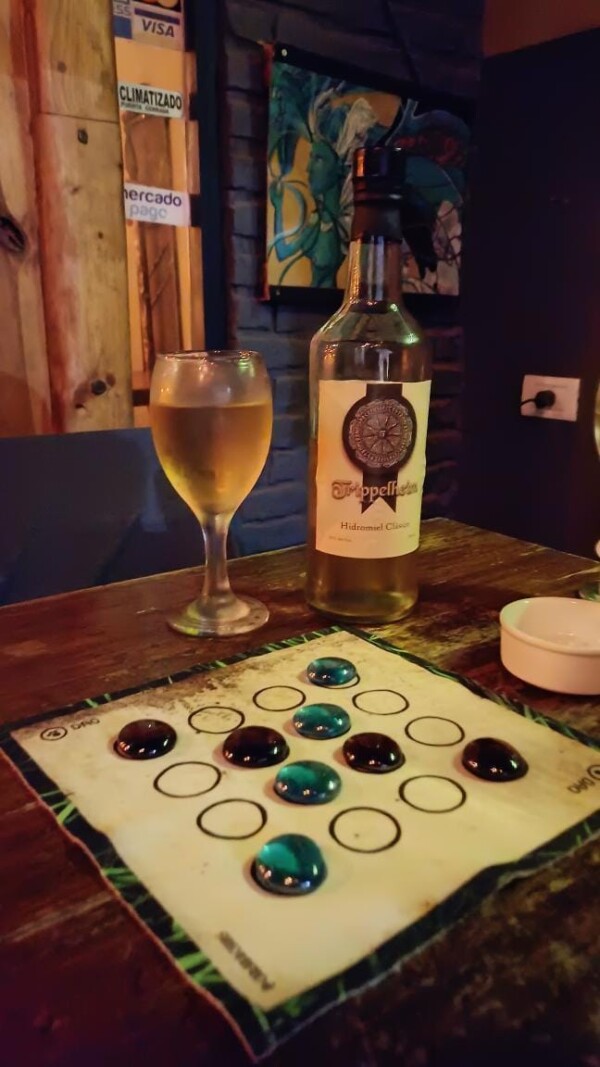 Tablero del Dao de Carabachuis desplegado en mesa de bar, junto a una copa y botella de bebida
