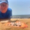 Roberto en la playa junto al Neutrón de Carabachuis, juego abstracto portátil con tablero extendido sobre la arena