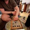 Jugador moviendo fichas en el tablero del Neutrón de Carabachuis en Los Ángeles, juego abstracto portátil.