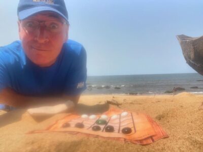 Roberto en la playa junto al Neutrón de Carabachuis, juego abstracto portátil con tablero extendido sobre la arena