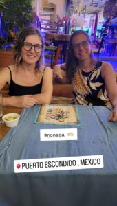 Juego de mesa Nonaga desplegado en bar, jugado por dos mujeres en un viaje
