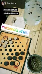 Juego abstracto Keru acompañado de una copa y un mate en mesa de bar, partida en curso