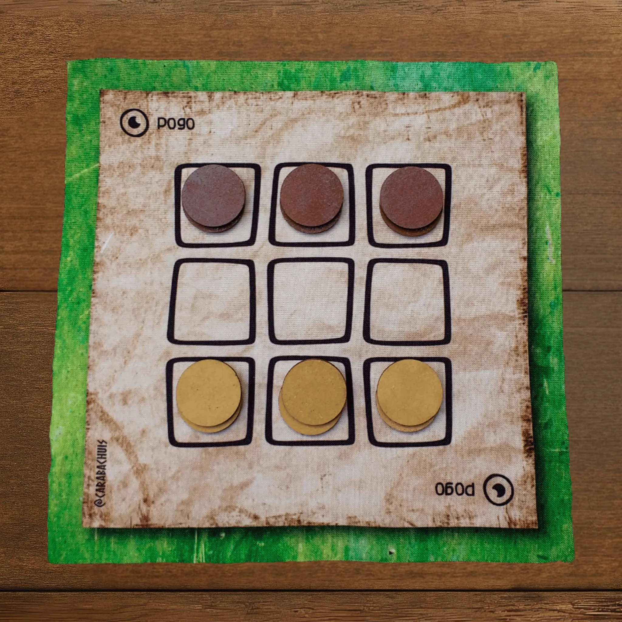 Tablero de Pogo extendido sobre una mesa de madera, las piezas están dispuestas en la posición inicial.