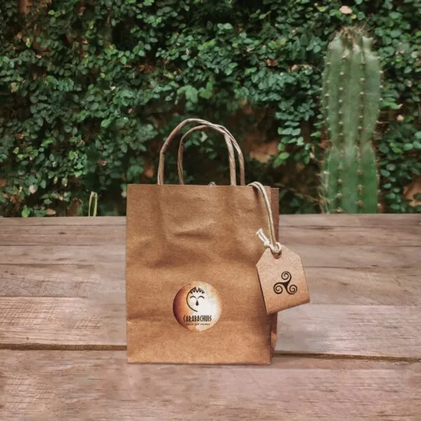 El Nonaga en su packaging ya listo para entregarse, bolsa de papel madera con logo de Carabachuis sobre mesa de madera